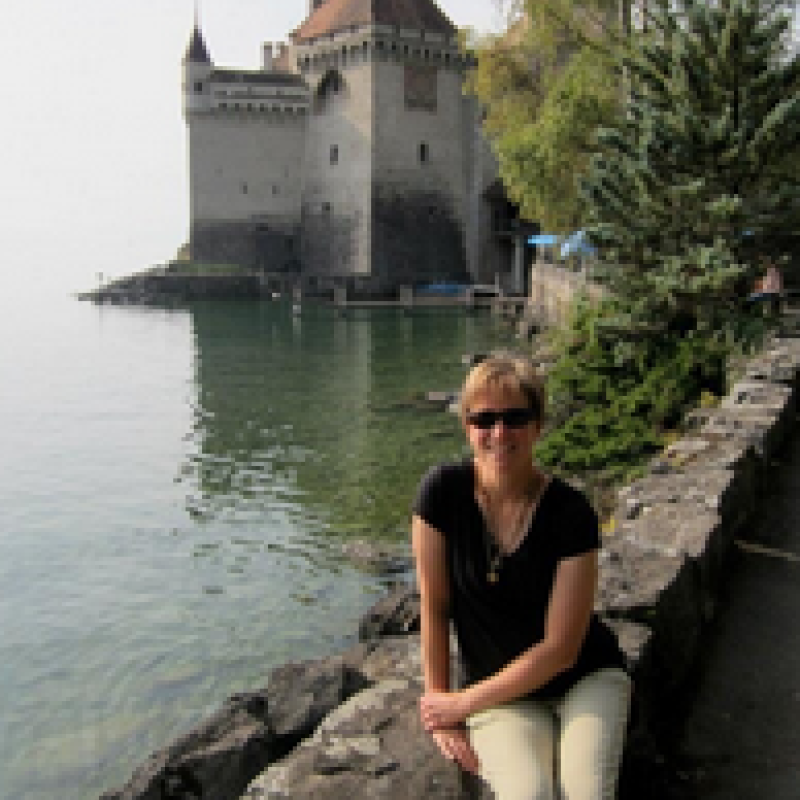 Shannon Featherstone seated on wall in front of small castle on the water.