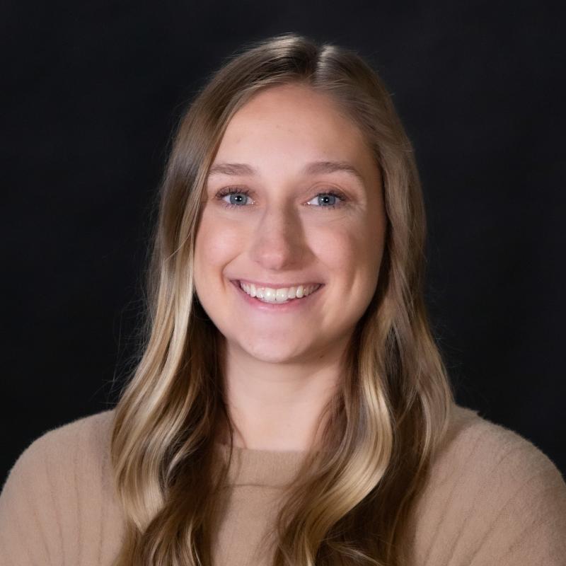 Smiling woman with blonde hair wearing a tan sweater. 