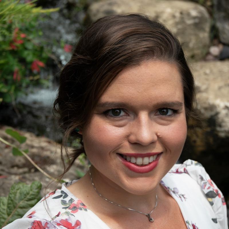 Dr. Cayla Rosché outside in front of rocks in a white floral dress.