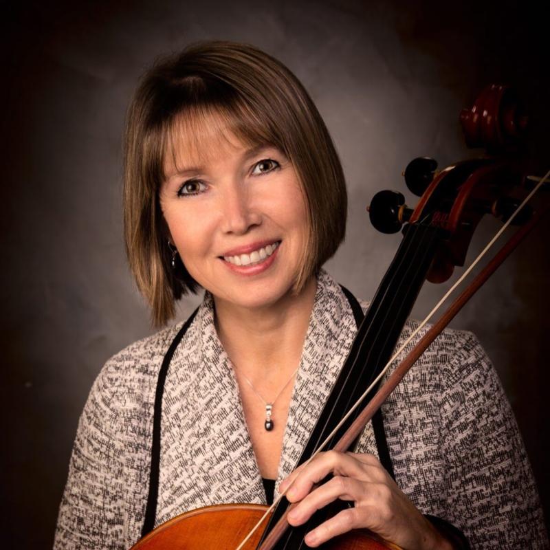 Brown haired woman holding cello smiling in professional headshot