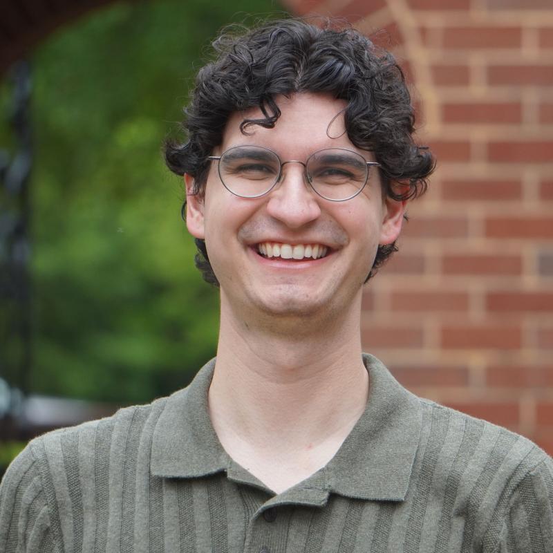 Headshot of Chandler Hall. He is smiling in front of a brick arch.