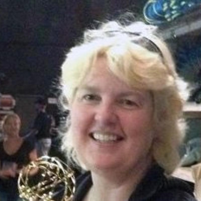 Head shot of blonde woman with sunglasses on her head.