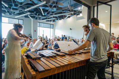Three instrumentalists perform in Fox Commons to a large crowd