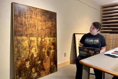 Val Muzzarelli takes notes on a large piece of art.