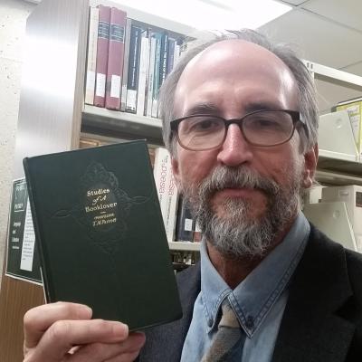 Pete holding a book with the title, Studies of a Booklover