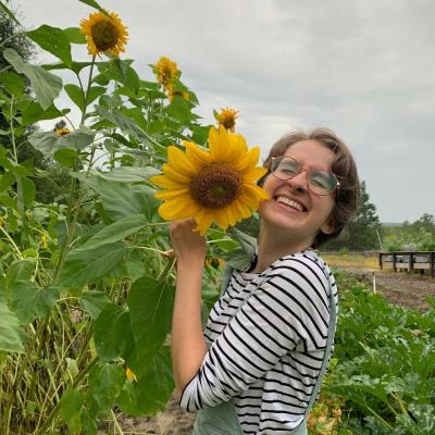 Headshot with sunflower of Avery Riel