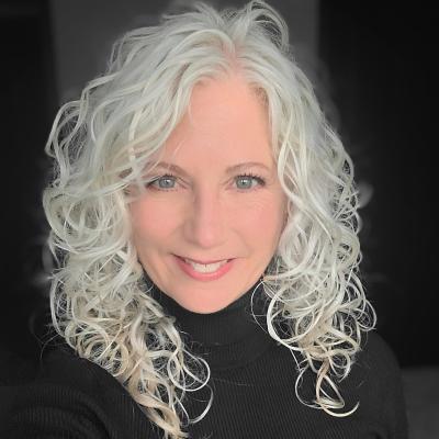 Headshot of Lori Fares, white woman with white hair in black turtle neck sweater.