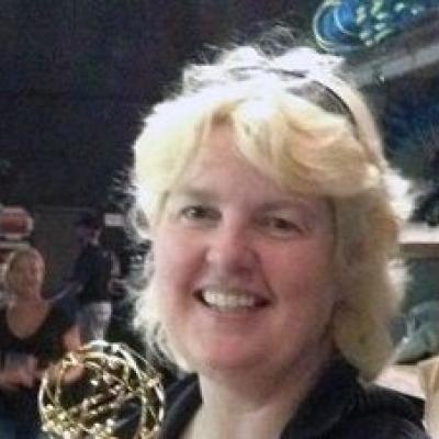 Head shot of blonde woman with sunglasses on her head.