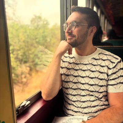 Photo of Mason, seated with black and white striped sweater and looking out a window