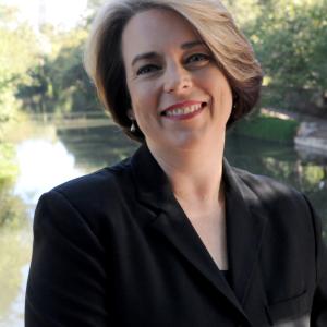 Photo of Professor Kristin Roach wearing a black jacket in sunshine by a river. Photo credit Kristian Jaime.
