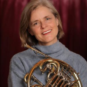 Woman with white hair holding a French horn 