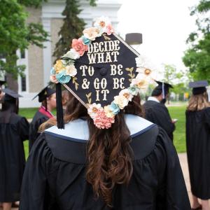 Decorated cap with words "Decide what to be and go be it" printed across the top and surrounded by flowers.