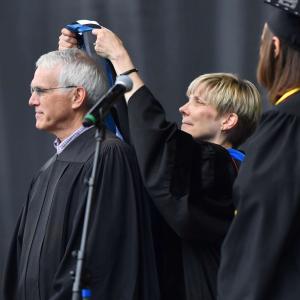 Faculty placing stole on another faculty member during Commencement.