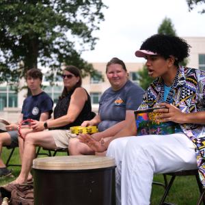 A student teaches others how to play drums.