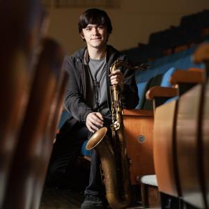 Jasper Kashou, a senior music performance and music education double major, sits for a portrait in Memorial Chapel with his saxophone.