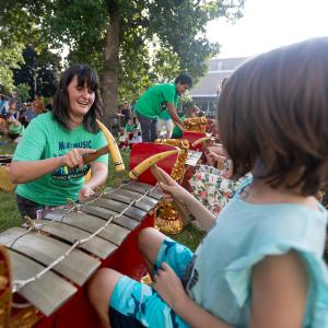 A woman teaching a child how to play gamelan.