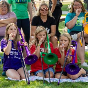 Children and adults having fun learning how to play pBone at Mile of Music's Music Education event outdoors.