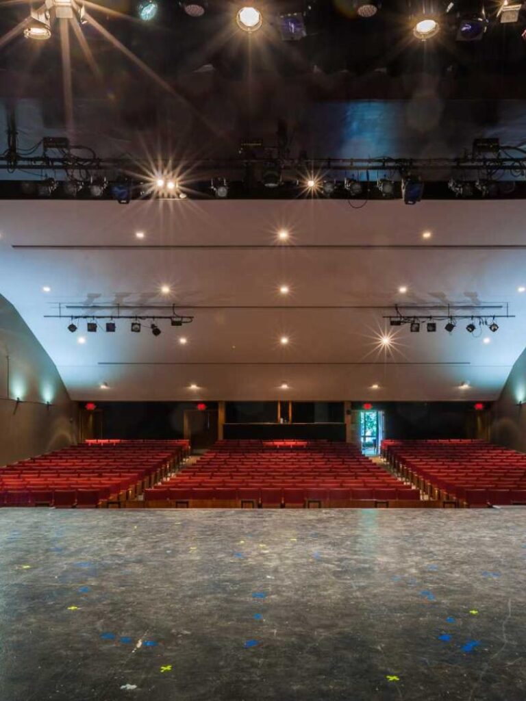 View from a stage looking out over rows of empty theater seats toward the back of the auditorium.